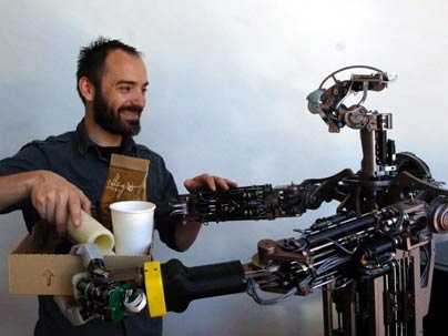 MIT postdoctoral associate Aaron Edsinger gets some help from Domo, an assistive robot he has been developing for the last three years.