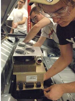 Mechanical engineering students Craig Wildman G, backround and Ryan King '09, center, and Jeremy Kuempel '10 work on putting together the porsche in Sloan Automotive Lab. They are installing a motor controller into the rear trunk compartment of the vehicle.