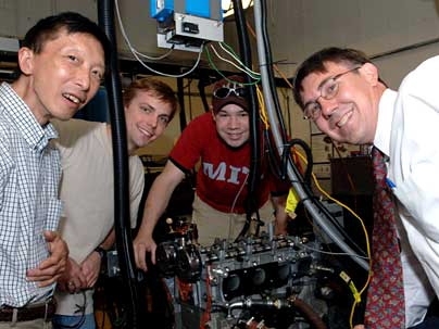 Mechanical engineering professor Professor Wai K. Cheng, chemical engineering graduate student John Angelos, mechanical engineering graduate student Nathan Anderson, and chemical engineering professor William H. Green, Jr. in lab with the engine they are working with to increase fuel efficiency.