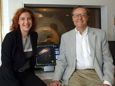 Noa Ofen, a post-doc in MIT's McGovern Institute for Brain Research and Department of Brain and Cognitive Sciences, and Professor John Gabrieli, co-director of the Clinical Research Center in the same department and associate member of the McGovern Institute, sit by a monitor displaying an image of a child's brain, which was taken usng the MRI scanning machine behind them.