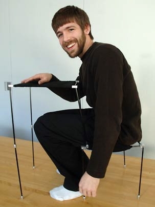 Graduate student Adam Kumpf sits on the chair at the desk that he has made part of his clothing for the MIT visual design class Give Me Shelter.