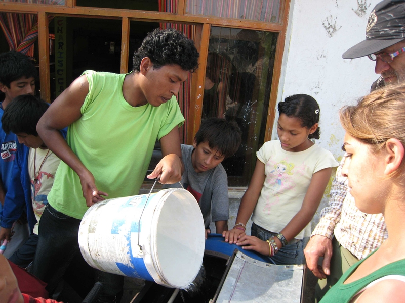MIT students and residents of Ventanilla, Peru work on the bicilavadora, a novel, inexpensive bike/washing machine.
