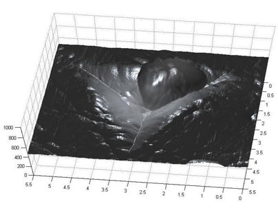 The image shows the imprint left by a nanoindenter in a particle of cement paste. The round blob at the top center is actually an extremely fine piece of dust on the surface.