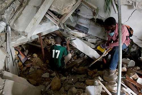 Two Haitians use crowbars, shovels and their hands to clear rubble in an attempt to reach survivors at the Montana hotel that collapsed after an earthquake.