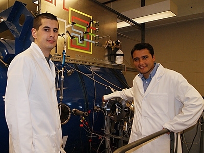 Dan Courtney, a PhD candidate, (left) and Lozano (right) near a vacuum facility that is used to test the system.