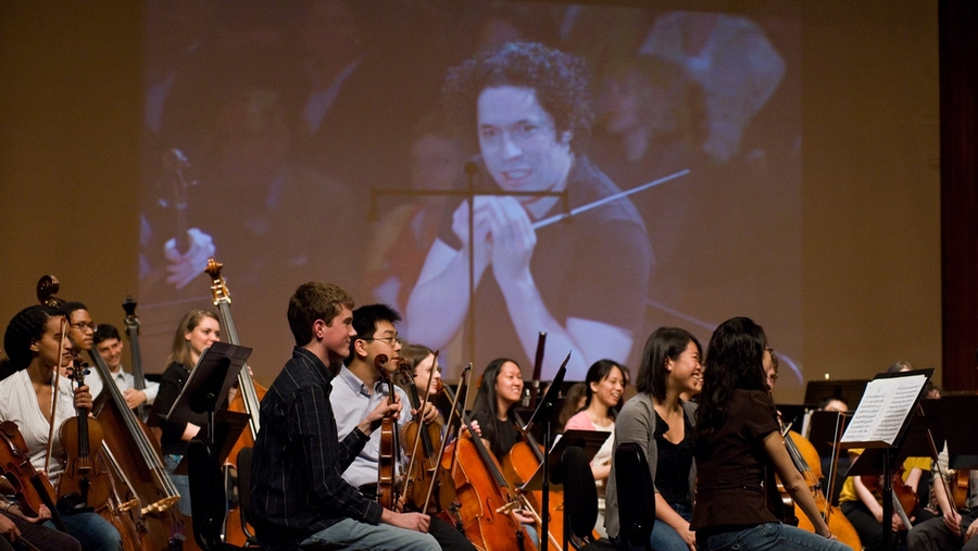A rear projection gives the Kresge Audience a close up view as McDermott Award winner Gustavo Dudamel works with the MIT Symphony Orchestra.