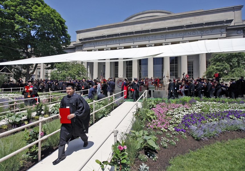 Two graduates walk off stage after receiving their diplomas.