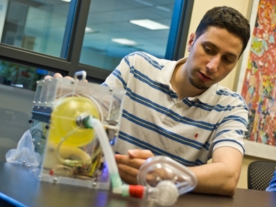 Graduate student Abdul al Husseini demonstrates the features of the mechanical ventilator he and his fellow students designed.