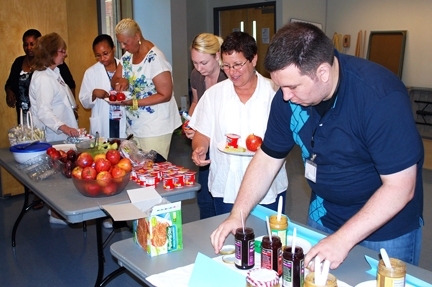Greg Baker, a health educator in Community Wellness at MIT Medical (far right), sets out peanut butter and other healthy foods as MIT Medical employees line up to help themselves during the Breakfast Challenge.