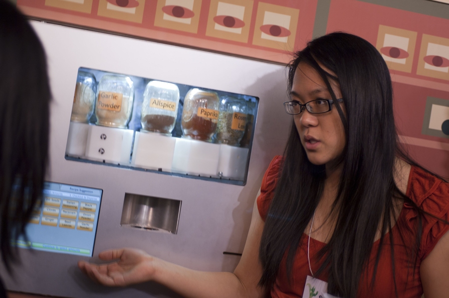 A member of the Orange team details how their spice-dispensing machine works to one of the presentation attendees.