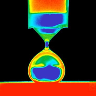 This color-enhanced image shows a droplet of water being deposited on a superhydrophobic surface, just before it separates from the dropper used to deposit it.