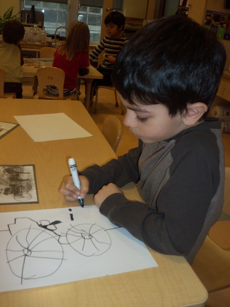 A preschooler at the Stata Technology Children's Center draws a picture of a mode of transportation used 150 years ago. 