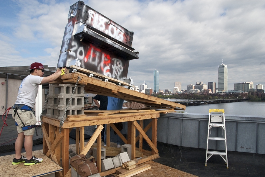MIT senior Andy Wu — safely tethered to the rooftop — gets ready to send the piano on its way.