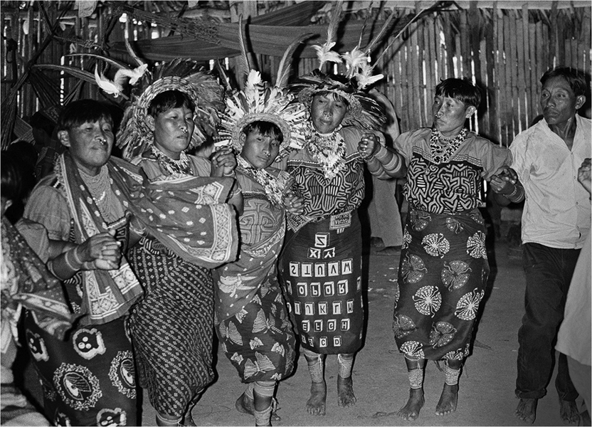 Women dance wearing feather headdresses.