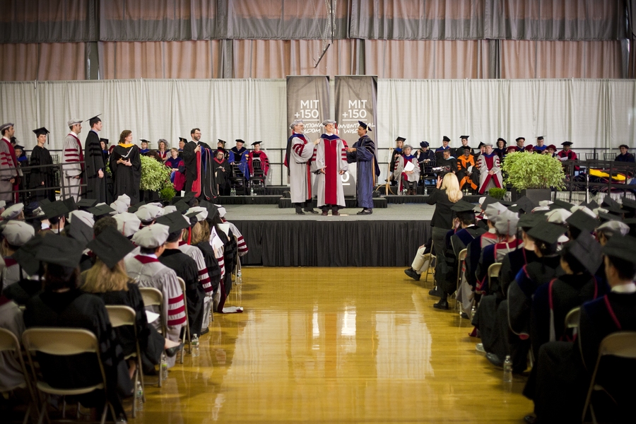 One of the students who earned a doctorate receives his hood.