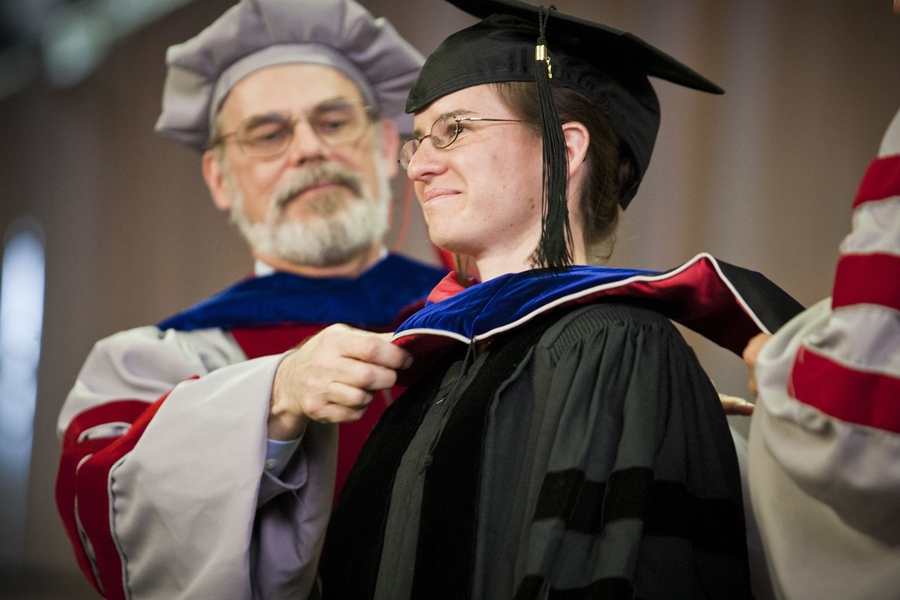 Chancellor Eric Grimson places a hood on one of the doctoral degree recipients.