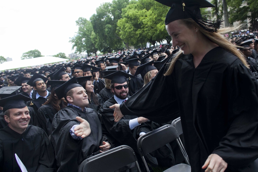 One graduate high-fives another on her way to her seat.