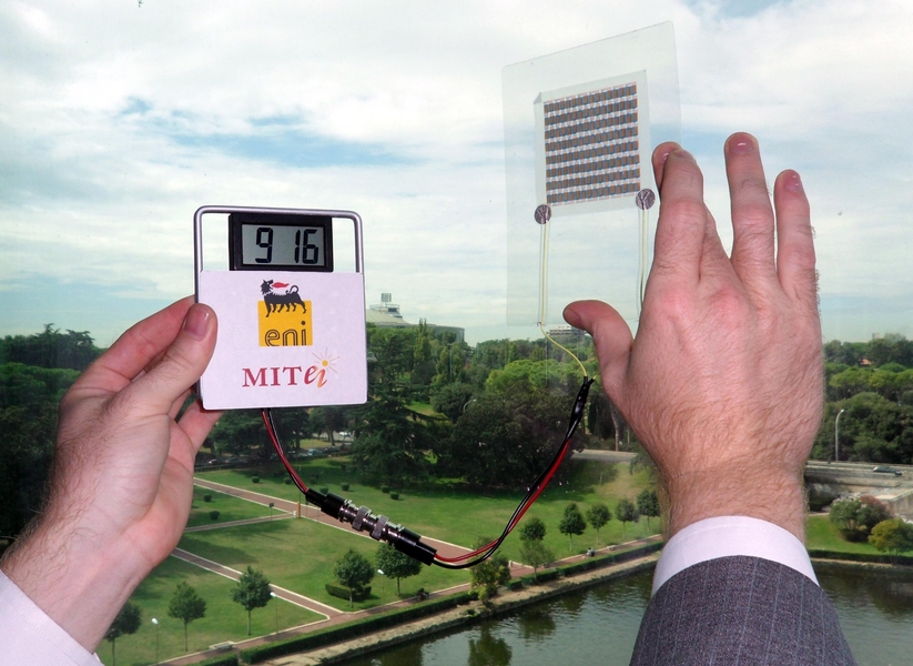 A paper solar cell, which has been laminated in plastic, is connected to an LCD screen to demonstrate that it is producing power from ambient sunlight.