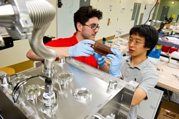 MIT senior Nicholas Dou, right, and his postdoctoral fellow advisor Ryan Enright discuss improvements to a cold plate that Dou has created to test condensation behavior and heat transfer properties of nanostructured surfaces. Using such novel surfaces, Dou aims to improve the performance of condensers, thereby increasing the efficiency of solar collectors.