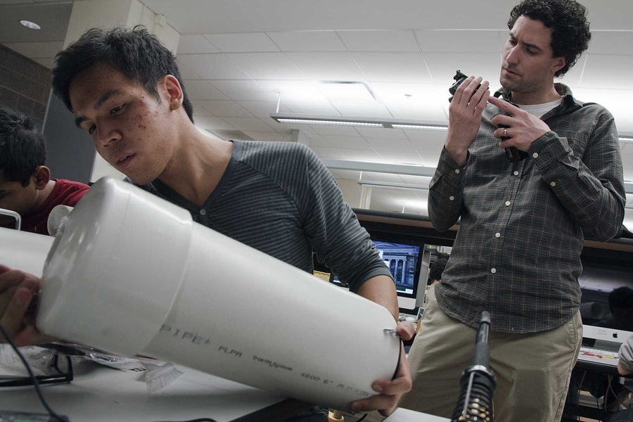 Bose engineer Mike Dellisanti inspects the soldering job on the switch-mode amplifier as graduate student Nathaniel Jay Salazar puts the finishing touches on his speaker.