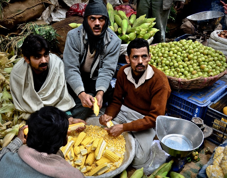 Men shell corn by hand in a market outside Delhi. Some Indian companies are exploring ways to convert agricultural waste into energy.