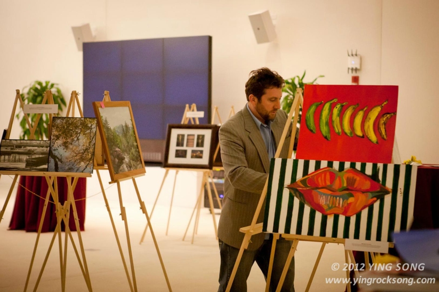 Sam Hunter Magee, coordinator of student art programs, displays student artwork at the Graduate Arts Soiree.