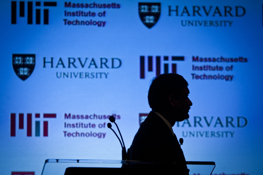 EdX President Anant Agarwal is seen silhouetted against a backdrop of the two universities' insignias at the start of a video describing edX.