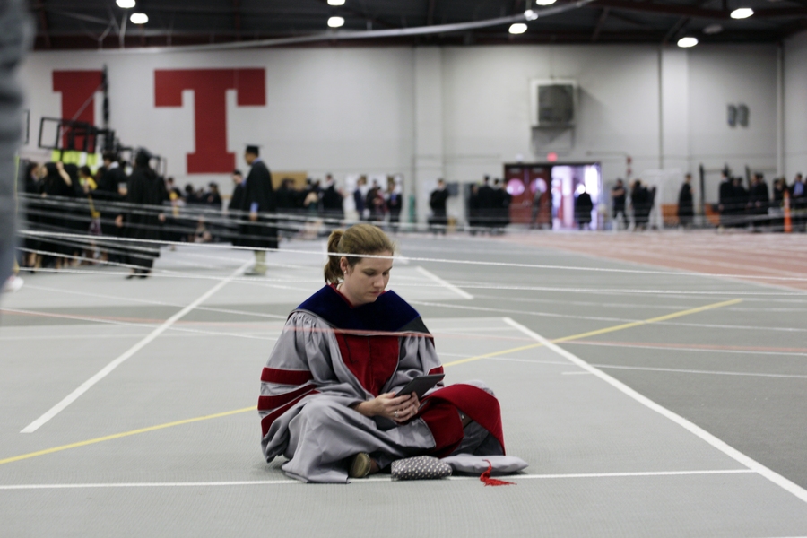 A doctoral student sits among the strings that separate out the students during the line up for procession.  