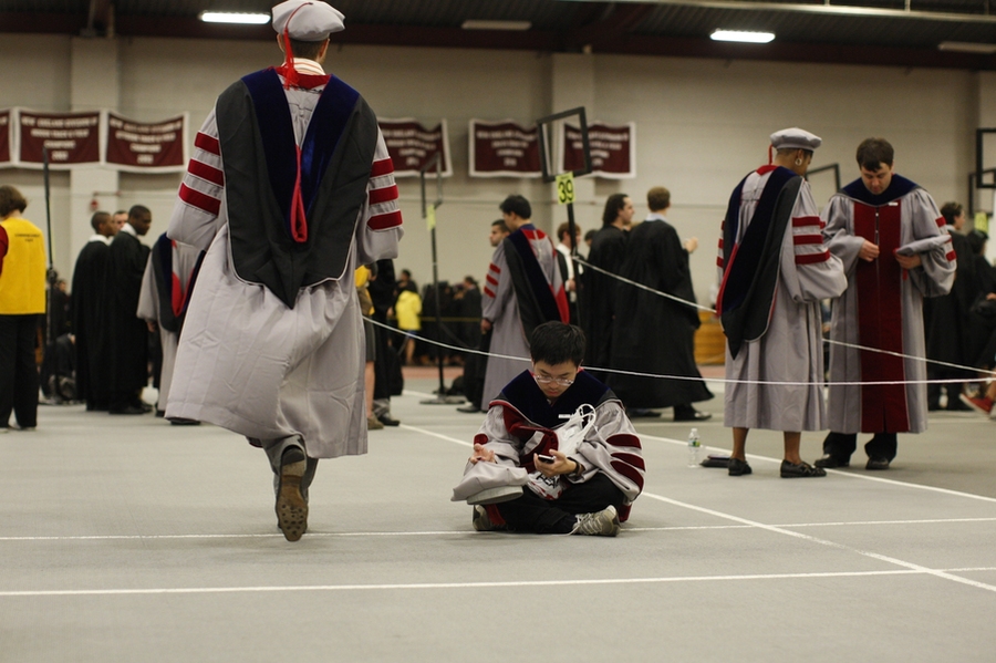 A doctoral student sits among the strings that separate out the students during the line up for procession.