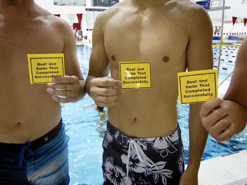 Students show off the cards they received after completing both the swim and boat test. 