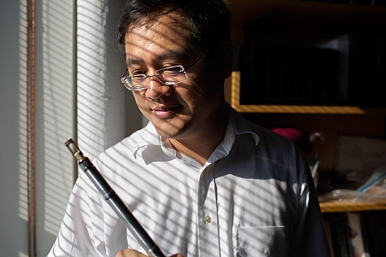 Ju Li, a professor in MIT’s departments of materials science and engineering and nuclear science and engineering, holds a scanning tunneling microscopy holder used in nanofactory in situ transmission electron microscopy.