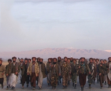 Photo of several dozen men in Afgan military garb with low mountains in the distance