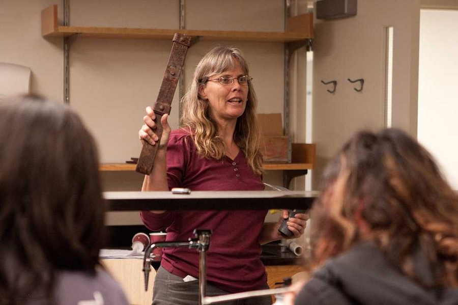 Amy shows students the type of leaf spring metal that was used to make hoe blades in Ghana.