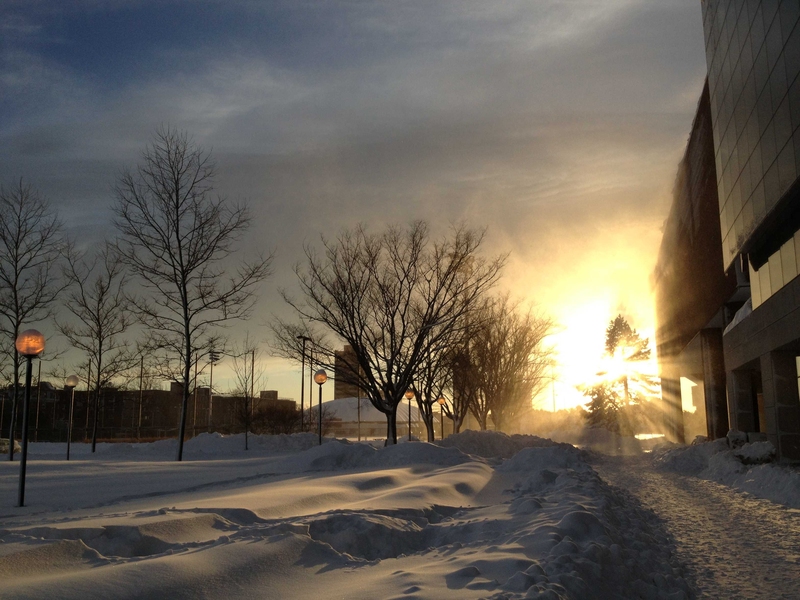 The sun sets over the snowy scene in front of the Zesiger Center (Building W35).