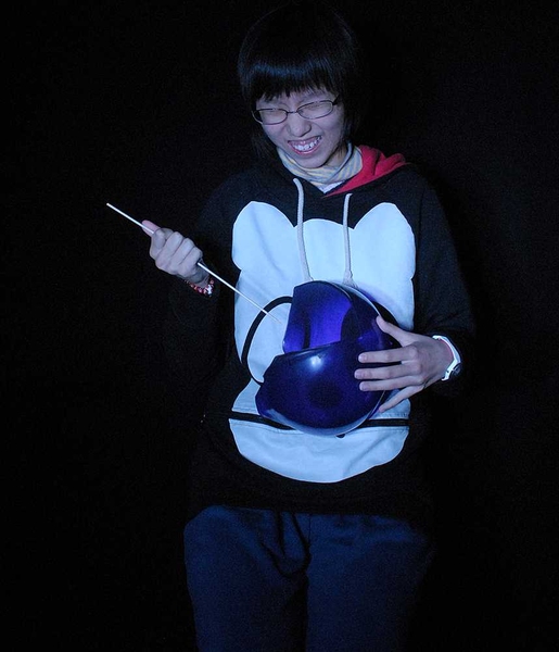 A student has his photo taken as he pops a balloon. The camera's flash is timed so that it catches the balloon half-popped. 