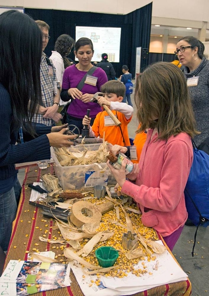 Researchers from MIT's D-Lab program provided hands-on experience with simple devices they have designed to speed corn shelling and, in background, to make charcoal briquettes from agricultural waste, by compressing the charred material in a mold, using a hammer.
