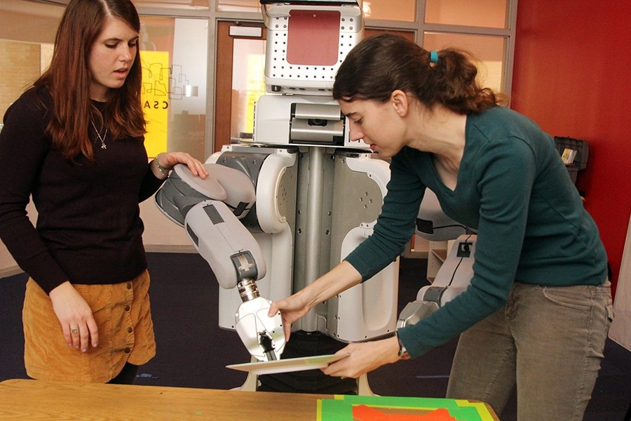 Annie Holladay (left) and Jennifer Barry with the Learning in Intelligent System Group's PR2 robot.