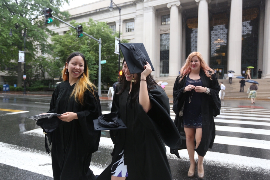 Several graduates cross Massachusetts Avenue in the rain on their way to Rockwell Cage, where graduating students assembled prior to the procession into Killian Court.