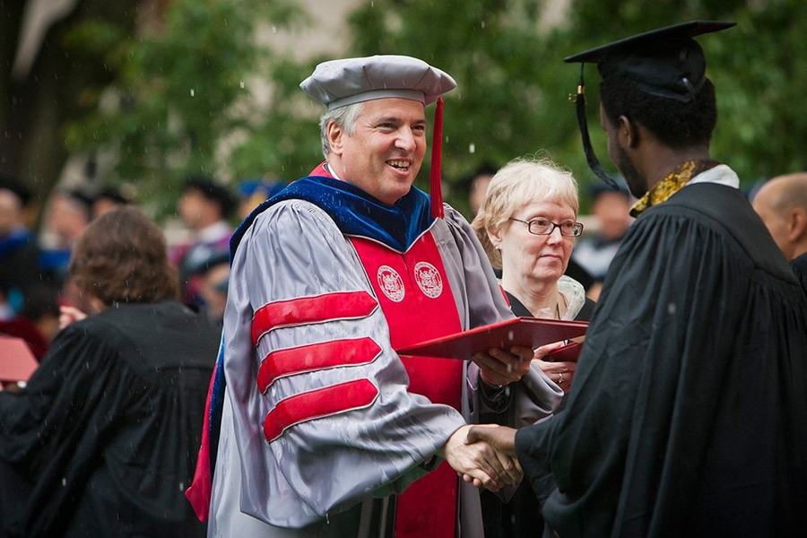 Provost Chris Kaiser hands a diploma to a graduate on stage.