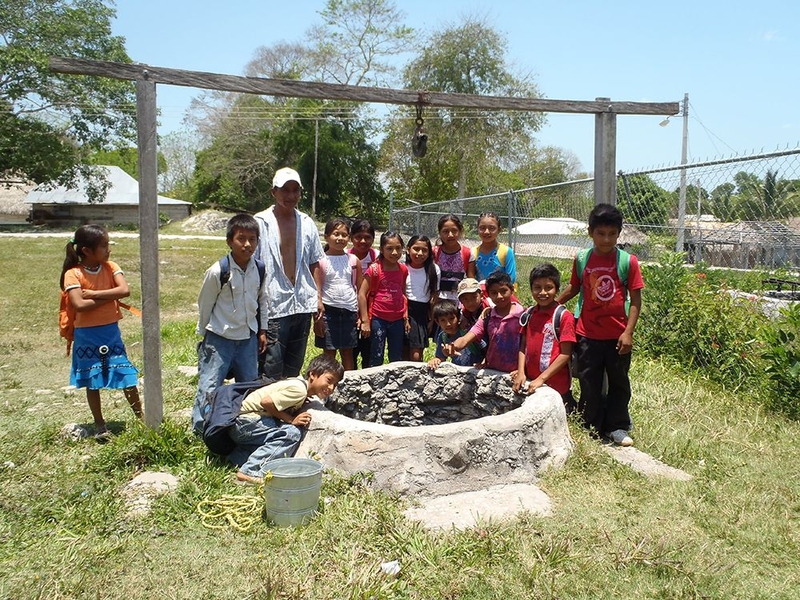 Schoolchildren pose by a village's well, whose water is too brackish for drinking.