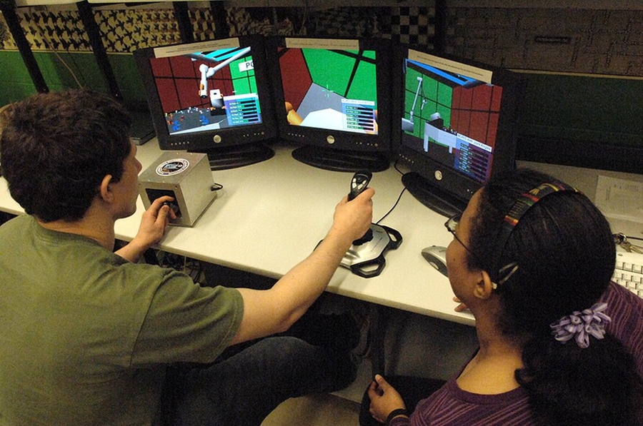 Volunteers work with MIT's simulation of the International Space Station's robotic arm.