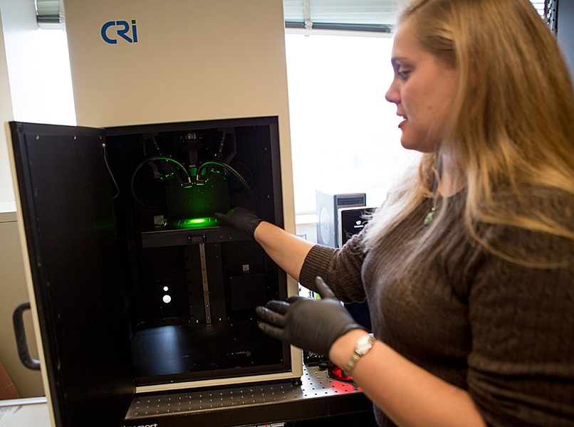 Postdoc Nicole Iverson demonstrates the instrument used to measure the fluorescent signal from nanotube sensors that detect nitric oxide.