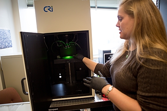 Postdoc Nicole Iverson demonstrates the instrument used to measure the fluorescent signal from nanotube sensors that detect nitric oxide.