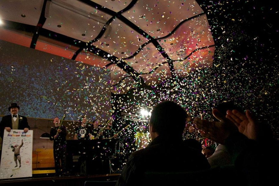 Professor David Wallace (left) displays a thank-you card presented to him by the class, while teaching assistants fire confetti cannons over the audience at Kresge Auditorium.
