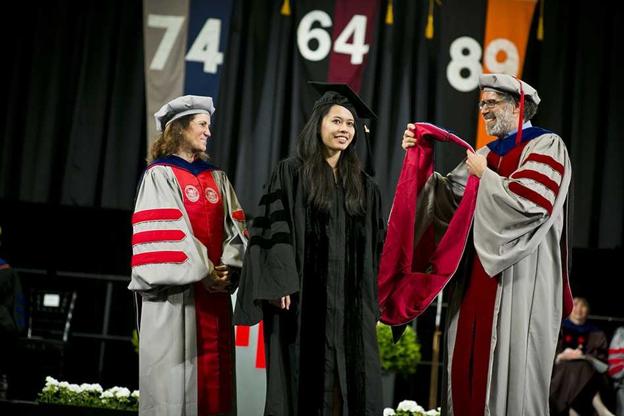 Chancellor Cynthia Barnhart (left) watches as Mitchel Resnick of the MIT Media Lab prepares to hood a degree candidate.