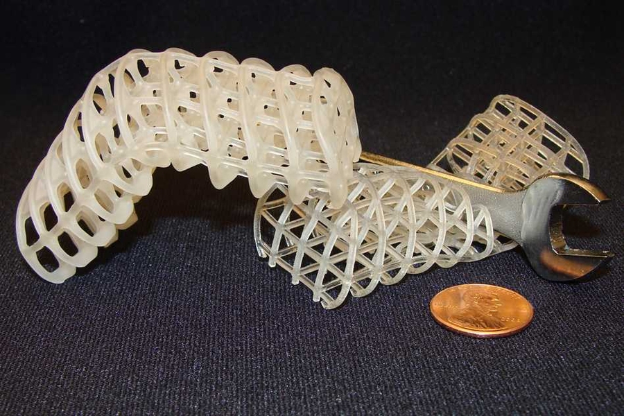 Two 3D-printed soft, flexible scaffolds: The one on the left is maintained in a rigid, bent position via a cooled, rigid wax coating, while the one on the right is uncoated and remains compliant (here, it collapses under a wrench).
