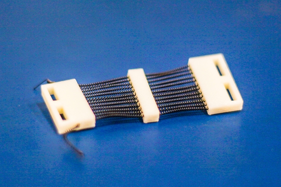 A close-up view of a 3-D-printed shape memory alloy (SMA) cartridge that packs 24 SMA actuators into a 1-inch-wide structure designed specifically for active compression garments.