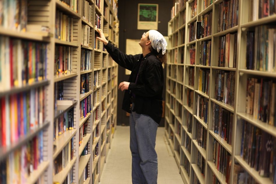 D. W. Rowlands, president and "skinner," goes through the stacks in the society library. The Society strives to acquire every new science-fiction publication for its collection, sometimes obtaining proofs before a book is officially published. 
