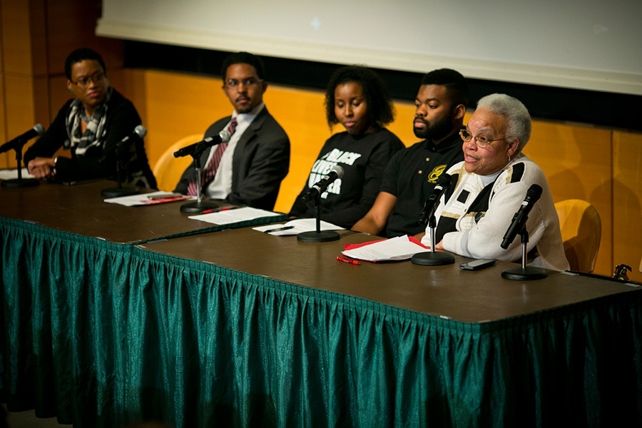 Five people sit at stage behind table with microphones
