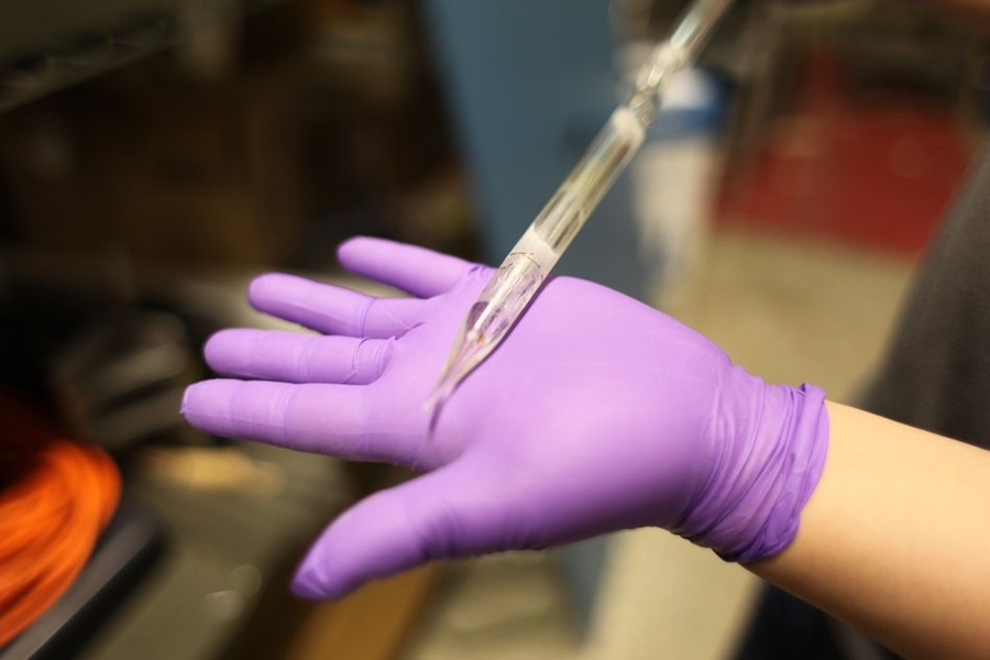 Hou holds a leftover silica preform after it has been used. The tapering tip shows how the preform is stretched to make long strands of fiber while in the furnace.
